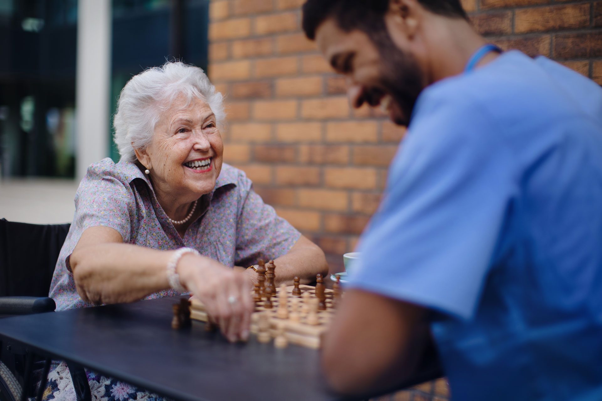 resident playing chess outside with staff member